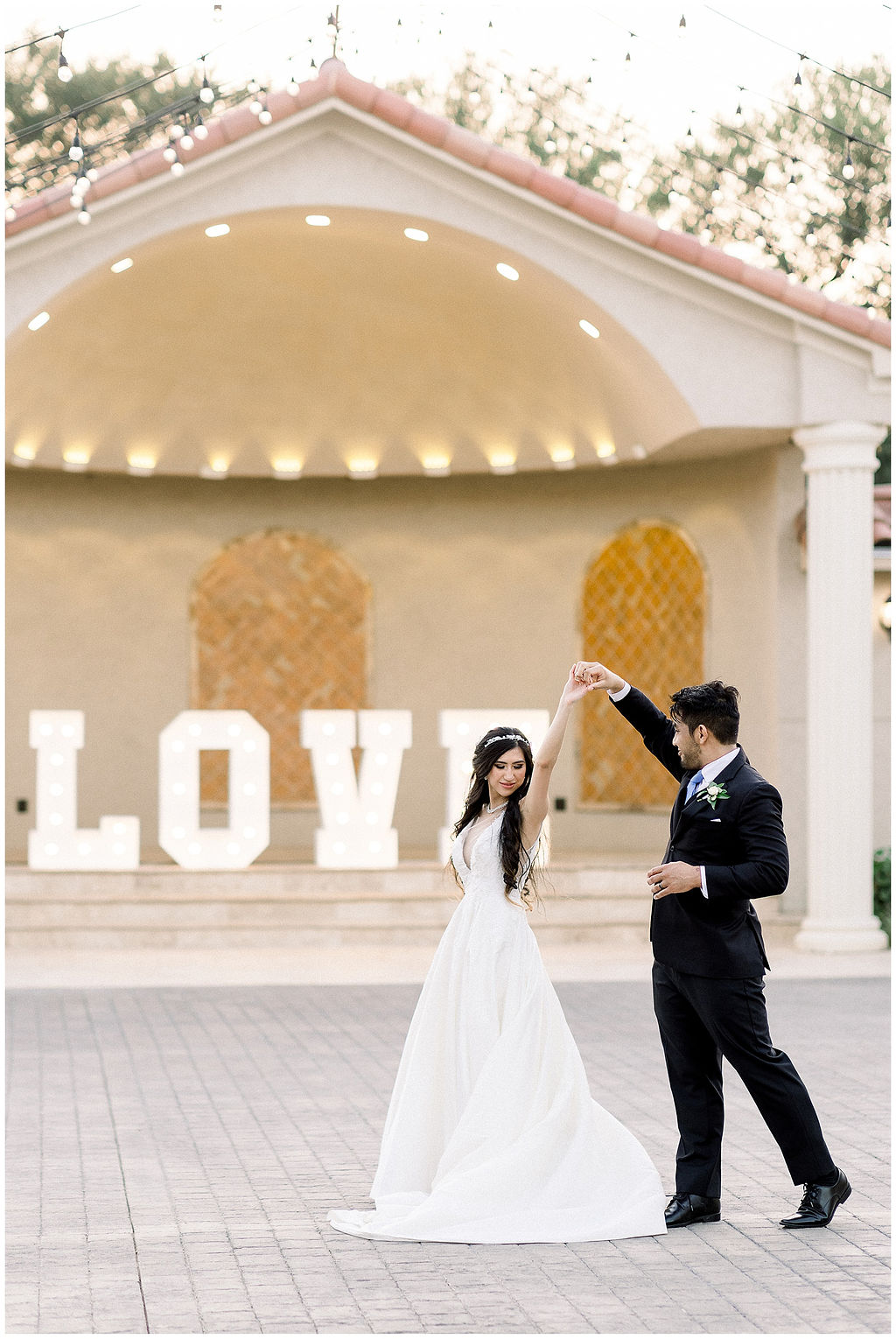 bride and groom dance in front of light up sign