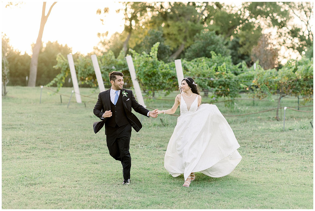bride and groom run through vineyard